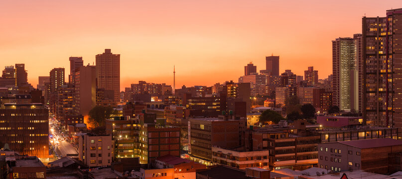A horizontal panoramic cityscape taken during a golden sunset, of the central business district of the city of Johannesburg, South Africa
