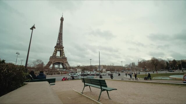 Paris, France - January, 2022: Eiffel Tower, Timelapse with fountain view from Jardins du Trocadero square. Cloudy sky in winter day at Tour Eiffel. Lot of tourists walking around.