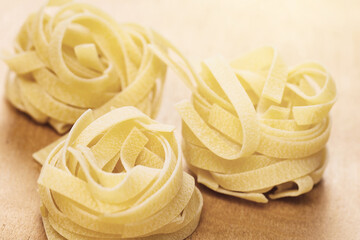 Uncooked tagliatelle pasta on wooden background