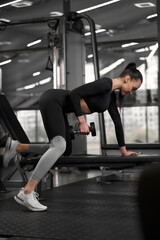 Fototapeta na wymiar Pretty positive woman fitness instructor wearing black tracksuit making training in contemporary gym