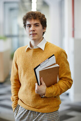Vertical waist up portrait of young man in office looking at camera, new employee and internship...