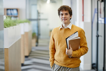 Waist up portrait of young man in office looking at camera, new employee and internship concept,...