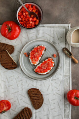 Simple sandwiches with cottage cheese, fresh tomatoes and hemp seeds. Healthy snacks with raw vegetables
Two toasts on a gray plate