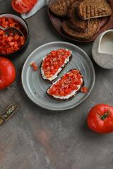 Simple sandwiches with cottage cheese, fresh tomatoes and hemp seeds. Healthy snacks with raw vegetables
Two toasts on a gray plate