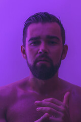 Handsome young man with wet skin in ultraviolet light