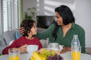 Little boy having breakfast with his mother at home.