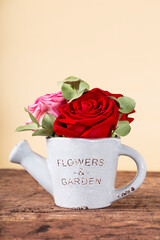 Valentines Day greeting card with free space for text. A bouquet of red roses in a pot on a wooden table, vertical photo