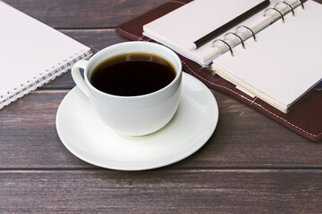 Coffee in a white cup on a wooden table against the background of documents. A break during work. business concept