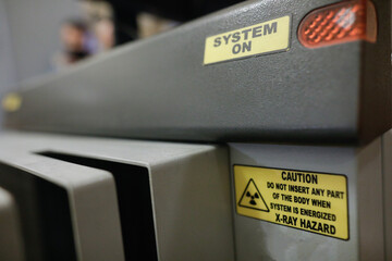 Shallow depth of field (selective focus) details with the Caution message on an X-ray baggage scanner machine. - obrazy, fototapety, plakaty