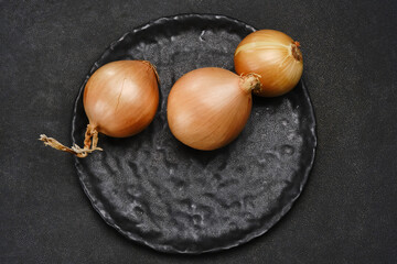 Head of onions on a black plate. Shallow depth of field