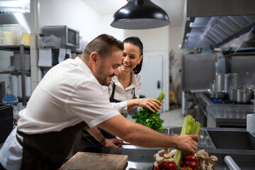 Chefs preparing vegetables for cutting in commercial kitchen.