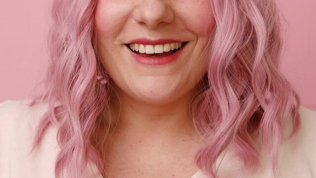Positive dreamy young pink hair woman sending air kiss to camera isolated over pink background