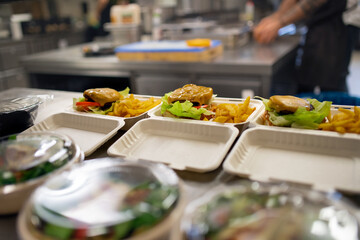 Meals in containers prepared for take away in kitchen restaurant. - obrazy, fototapety, plakaty