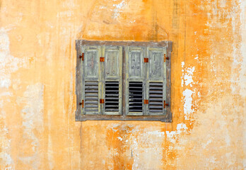 Retro style yellow window with shattered glass on dirty damaged white walls. Detail of window in abandoned rural house
