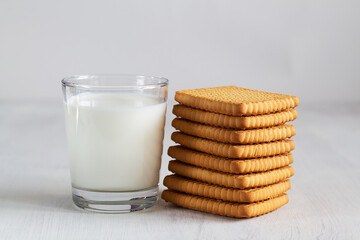 glass of milk and cookies.stacks of tasty cookies on the white. square biscuits on the white table with copy space. healthy eating.