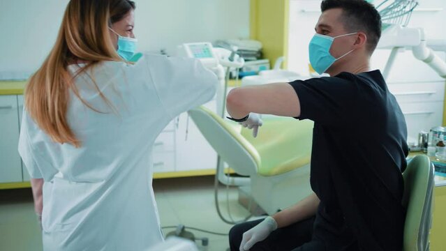 Dentist and nurse in protective face mask greet their elbow, new greeting to avoid spread of coronavirus. Social distancing. 