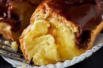 Eating eclair with chocolate from a dark slate