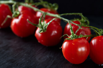 Small red cherry tomatoes on dark slate