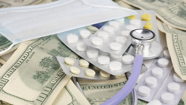 Dollars, medical stethoscope, mask and pills in blisters