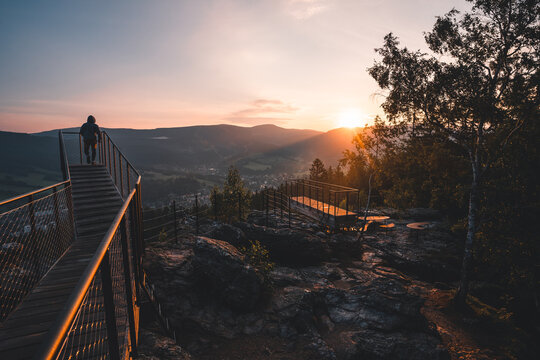 Man standing on a new and modern lookout forest park The Guard Patrol, Czech: Straz, while watching sunrise, Sunrise on Straznik Hill above Rokytnice nad Jizerou, Giant Mountains National Park