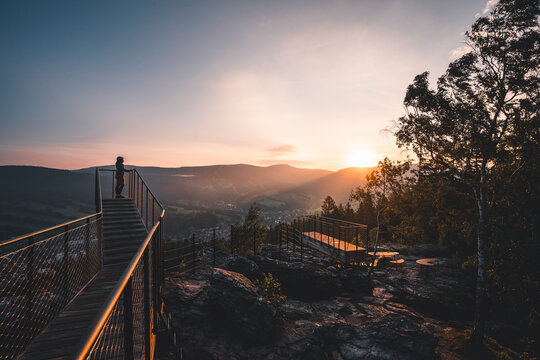 Man standing on a new and modern lookout forest park The Guard Patrol, Czech: Straz, while watching sunrise, Sunrise on Straznik Hill above Rokytnice nad Jizerou, Giant Mountains National Park