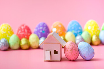 Stylish Easter eggs and a house on a pink background. Family holiday concept. Greeting card template. copy space. banner
