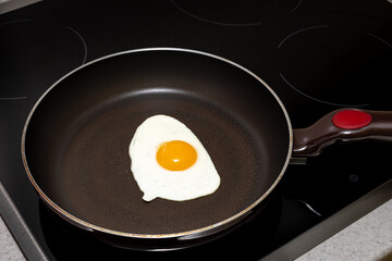 frying pan on the hob with fried eggs from one egg with yolk