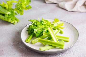 Sliced fresh celery stalk with leaves on a plate on the table ready to eat. Vegetarian food