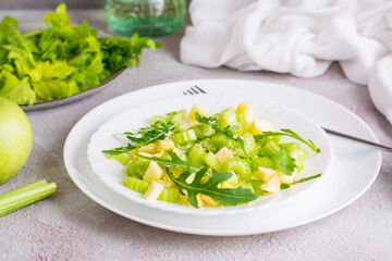 Dietary salad of celery, green apple, arugula and sesame seeds on plates on the table. Vegetarian food