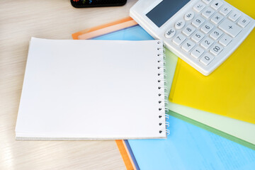 Notepad with space for text on color files near white calculator. business concept