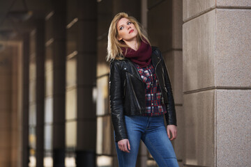 Fototapeta premium Young fashion blonde woman in black leather jacket and snood scarf