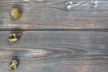 Easter background. Three quail eggs on the left against a dark wood background.
