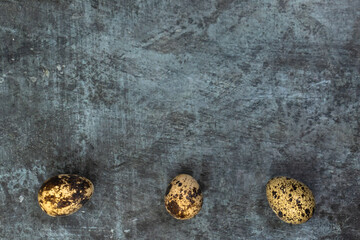 Easter background. Three feathery eggs at the bottom against a dark background.