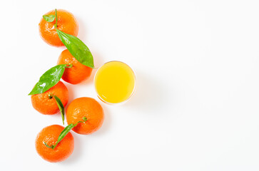 Mandarines, tangerine, clementine with leaves on and a glass of orange juice with white background. Top view


