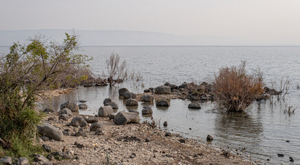 Rocks on the shore and the  Sea of Galilee   as seen from the trail along the western coast of the lake, Lake Kinneret, Galilee, Israel - obrazy, fototapety, plakaty