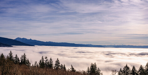 Dense winter cloud inversion seen from a mountaintop residence looks like stormy ocean with mountain backdrop in silhouette.