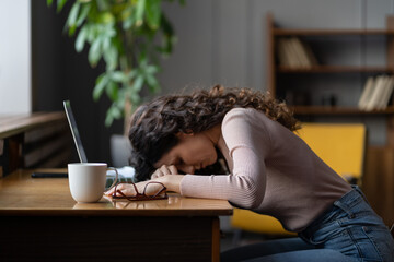 Overworked tired female student, freelancer or remote worker sleep lying on desk suffer from...