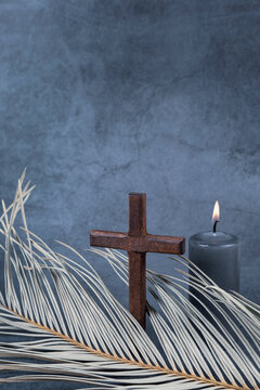 Catholic Cross with palm leaf and burning candle. Ash Wednesday, Lent season, Holy Week, Good Friday and Palm Sunday concept. Copy space.