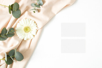 Mockup business card with eucalyptus leaves, gerbera and nude fabric