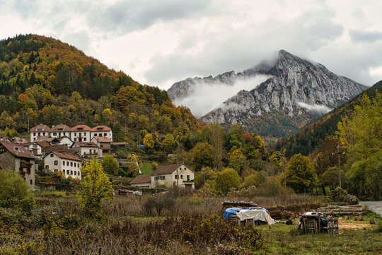 autumnal view of the town of Isaba with the mountain and its peak in the background surrounded by clouds, in the Navarrese Pyrenees