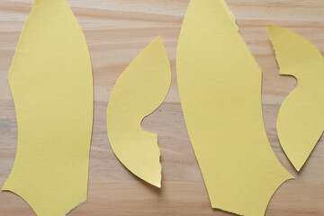 torn and cut yellow paper shapes on wood