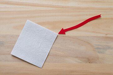 red arrow with paper square on a wooden surface