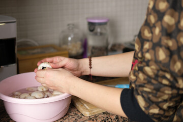 Woman cleaning edible mushrooms in a bowl in the kitchen, food preparation composition for dinner. Fresh and raw mushrooms in a bowl of water. 