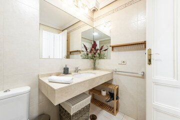 Bathroom with cream marble top, porcelain sink and built-in mirror in vacation rental apartment