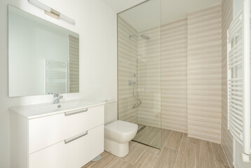 Toilet With white bathroom furniture, sink under the square glass mirror and shower with glass partition with ceramic stoneware floors
