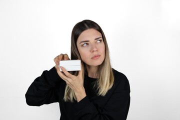 Fototapeta premium Waist up portrait of pretty young blonde girl in casual clothes trying to guess her present. Isolated on white background. Surprise, jewellery, gift and valentine's day concept.