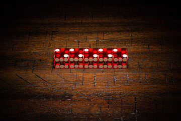 Red professional casino-style dice on a wooden table with high-key lighting. 