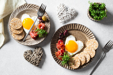 Romantic Breakfast on Women's Day - fried eggs in the shape of a heart and olives. Healthy breakfast. Rice cakes with eggs and hamon. Romantic breakfast. Top view.