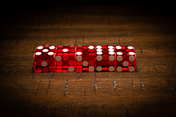 Red professional casino-style dice on a wooden table with high-key lighting. 