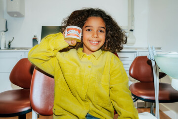 Afro-American girl smiling holding a denture mold. 